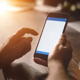 Cropped Hands Of Man Using Phone On Table